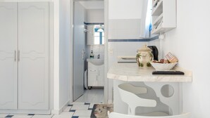 Een moderne keuken met witte kastjes, een marmeren aanrechtblad en uitzicht op de aangrenzende badkamer.