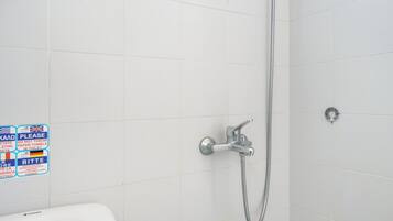 Een badkamer met witte tegels, een douche met handdouche en een wastafel.