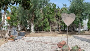Un giardino con piante in vaso, un cartello a forma di cuore e una statua.