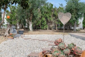 Ein Garten mit Topfpflanzen, einem herzförmigen Schild und einer Statue.