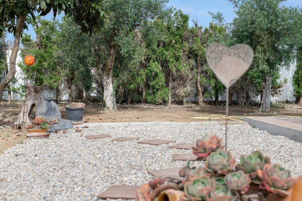 Ein Garten mit Topfpflanzen, einem herzförmigen Schild und einer Statue.