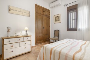 Ein Schlafzimmer mit Bett, Schminktisch, Stuhl, Kleiderschrank und einem motivierenden Spruch an der Wand.