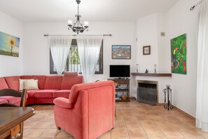 Ein Wohnzimmer mit einer Couch, Fernseher, Kamin und Kunstwerken an den Wänden.
