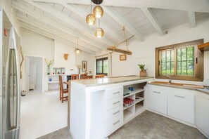 A spacious kitchen with a large island, white cabinetry, and pendant lighting. - Beautiful Villa in Siller (Port de Pollença)