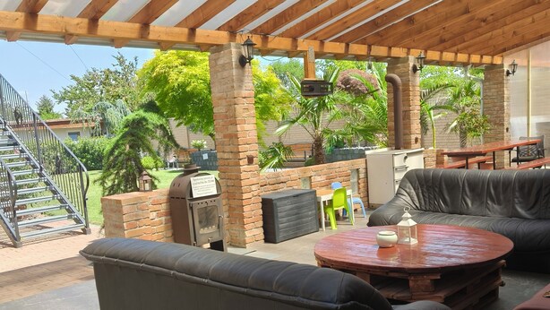 Un patio al aire libre con un espacio de estar techado, una parrilla y vistas del jardín circundante.