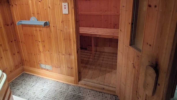 A wooden cabin interior with a bench, a door leading to a room, and a small window. - Worcester Haven - Charming Sunderland House (Sunderland)