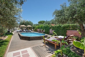 Ein Garten mit Swimmingpool, Liegestühlen und einer Holzterrasse.
