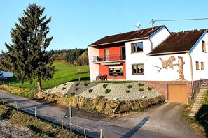 Een huis met twee verdiepingen, een balkon, een stenen muur en een grindpad.