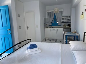 A bedroom with a bed, a bedside table, a chair, a small desk, a kitchenette, and a bathroom. - Giavasi Seaside 1 Country House with Sea View and Balcony (Finiki)