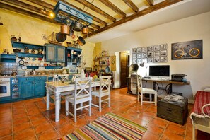 A kitchen with blue cabinets, a dining table with chairs, a colorful rug, and a vintage typewriter. - Holiday Home 'Wine & Piano Stories' with Private Terrace, Shared Garden and Wi-Fi (Esperii)