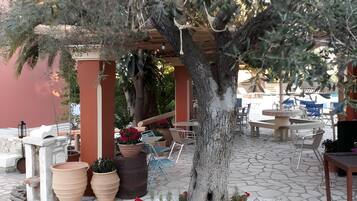 Un arbre agrémenté d’une pergola, avec des sièges extérieurs et des plantes en pot.