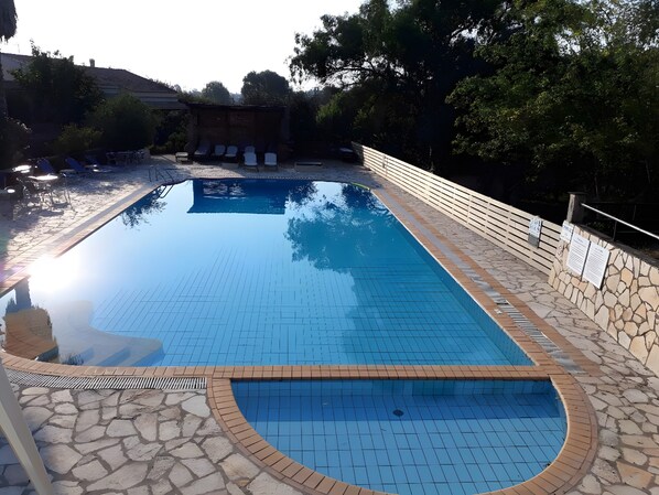 Una piscina rectangular con bordes de azulejos, rodeada de muros de piedra y una terraza de madera.