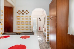 Zona pranzo con tavolo bianco, sottopiatti rossi e piastrelle decorate.