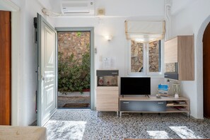 Una camera moderna con una parete in pietra, una televisione e un armadietto in legno.