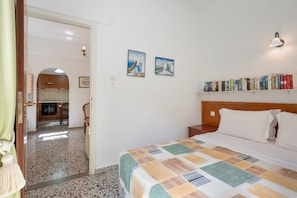 Camera d'albergo con un letto, una libreria, due quadri appesi al muro e vista sull'area cucina.