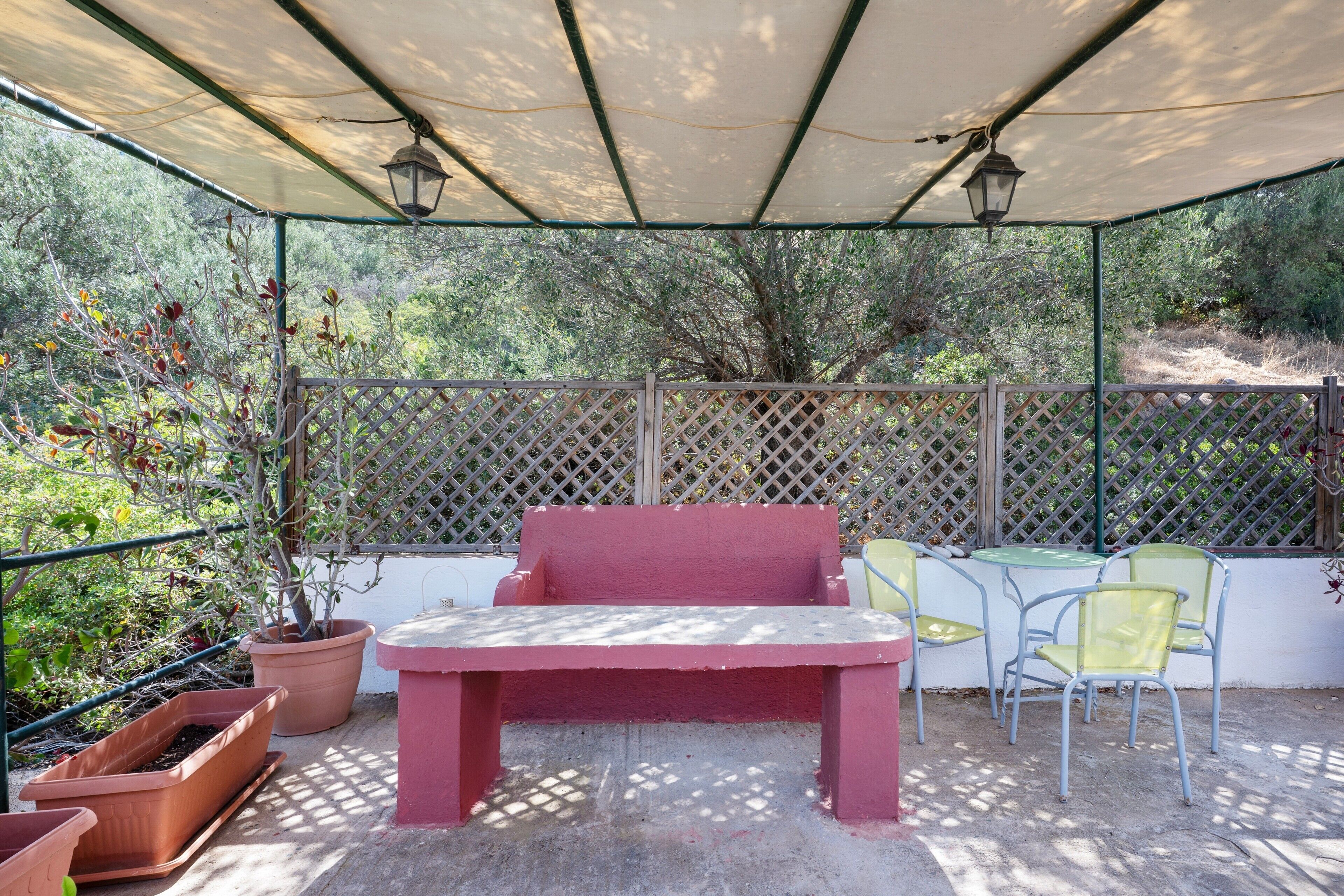 Eine Terrasse im Freien mit einer roten Bank, zwei gelben Stühlen und Topfpflanzen.