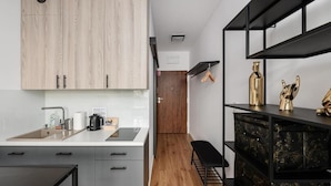 A modern kitchen with light wood cabinets, a black countertop, and a black bench. - ShortStayPoland Zgierska B106 (Warszawa)