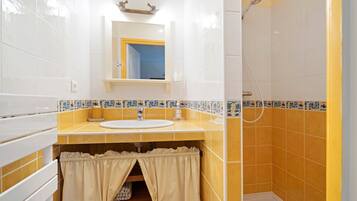 Ein Badezimmer mit Waschbecken, Spiegel, Dusche und gefliesten Wänden.