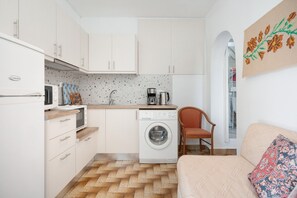 Een kleine keuken met een wasmachine, een magnetron en een koffiezetapparaat.