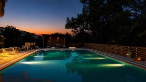 Ein Schwimmbad mit Holzterrasse, Liegestühlen und einem Holzzaun.