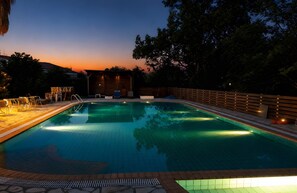 Ein Schwimmbad mit Holzterrasse, Liegestühlen und einem Holzzaun.