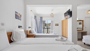 A hotel room with two beds, a TV, a desk, and a view of the outside.
