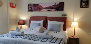 Ein Hotelzimmer mit Bett, zwei Nachttischlampen, einem Stadtbild und einem Wandzeichen.