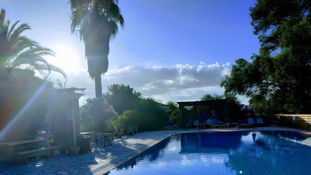 Una piscina con bordi piastrellati, sedie a sdraio e un’area salotto coperta.