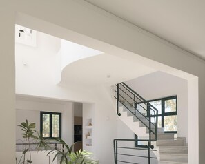 Ein modernes Interieur mit einer Treppe, einem Oberlicht und Blick ins Freie.