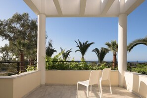 Ein Balkon mit Blick auf das Meer, umgeben von Palmen und viel Grün.