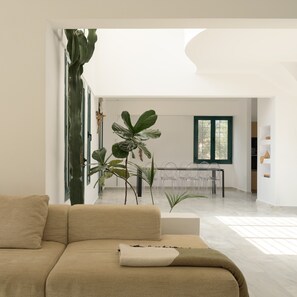 Ein modernes Wohnzimmer mit einer Couch, einem Essbereich mit Tisch und Stühlen und großen Fenstern für natürliches Licht.