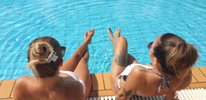 Zwei Personen entspannen am Pool mit klarem Wasser.