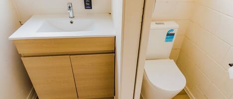 A small bathroom with a white sink, wooden vanity, and a white toilet.