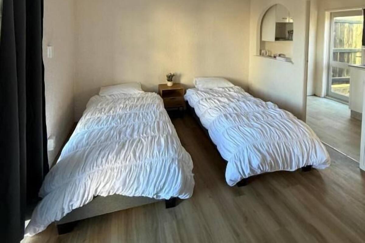 A room with two beds, a small table, and a mirror on the wall.
