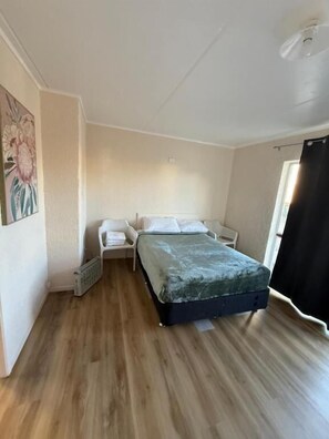 Una stanza con un letto, una sedia, un termosifone e una finestra.