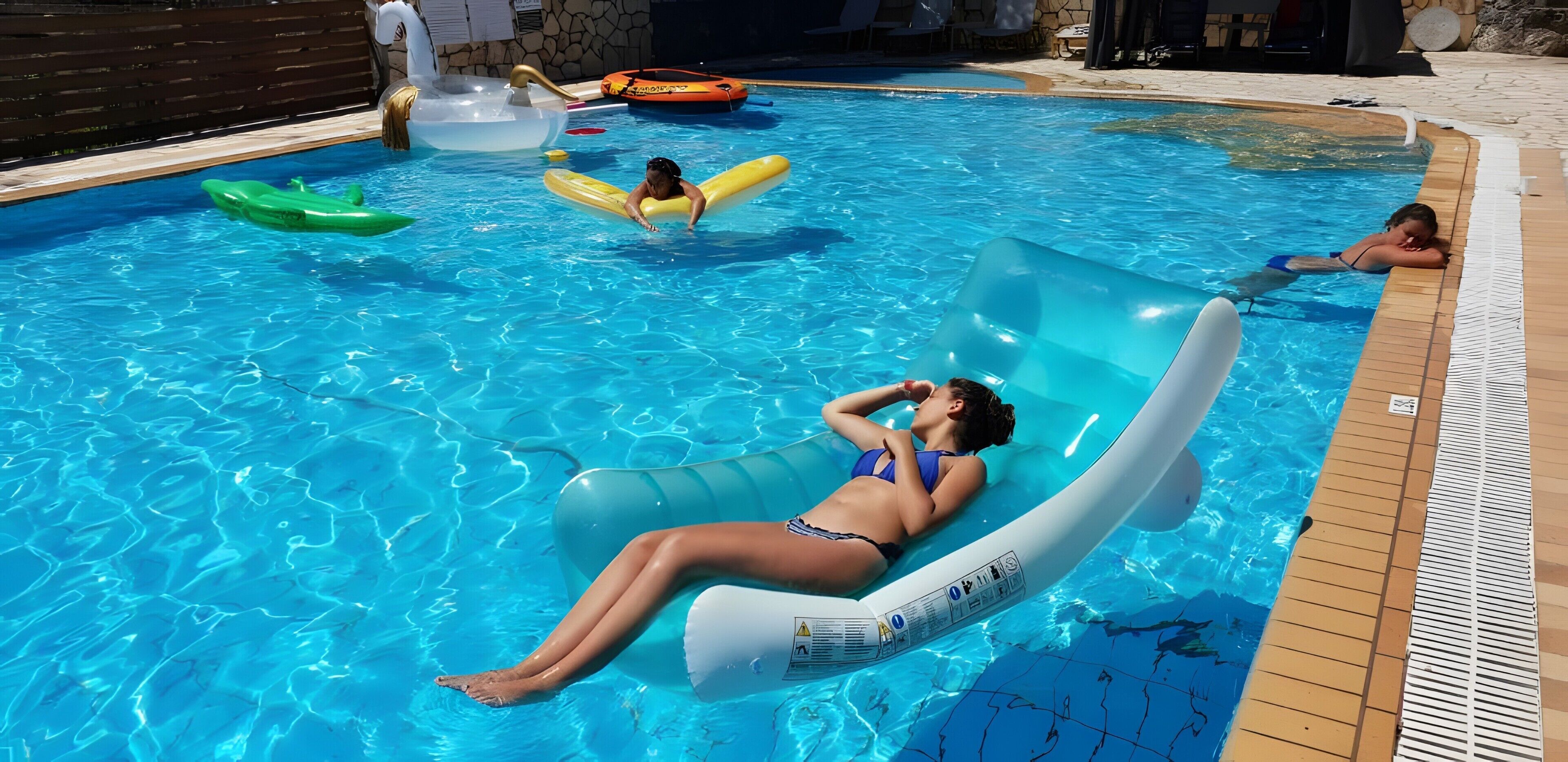 Une piscine avec des bouées gonflables et une terrasse carrelée.