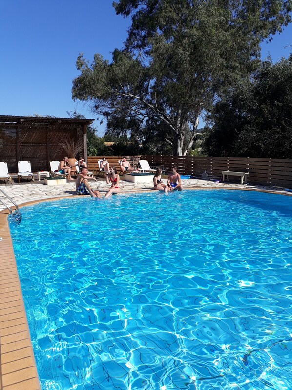 Una piscina con agua cristalina, rodeada de sillones de descanso y una terraza de madera.