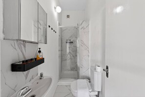 Uma casa de banho moderna com banheira, sanita e chuveiro.