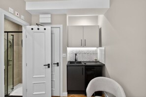 A compact kitchen with a sink, cabinets, and a chair. - Studio, West Kensington + Hammersmith (Greater London)