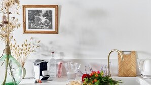 A kitchen counter with a coffee maker, a vase with dried flowers, a bouquet of fresh flowers, and a framed picture on the wall. - Château de la Piscine - Appartements dans le Mas au coeur d'un grand parc arboré (Montpellier)