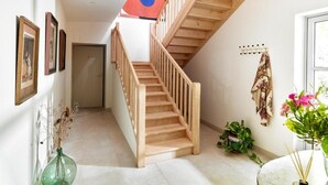 A staircase with wooden railings, a wall-mounted coat rack, and a door at the end. - Château de la Piscine - Appartements dans le Mas au coeur d'un grand parc arboré (Montpellier)