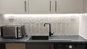 A compact kitchen with a microwave, sink, and dishwasher. - Studio, West Kensington + Hammersmith (Greater London)