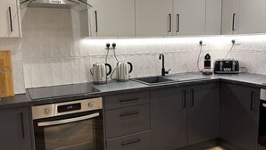 Een moderne keuken met een inbouwoven, een kookplaat, een spoelbak en een waterkoker.