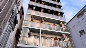 A multi-story building with balconies, a bicycle parking area, and a sign indicating a public restroom. - GrandPacific Ebisuhonmachi (Osaka)