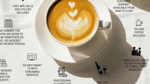 Valkoiselle aluslautaselle tarjoiltu kuppi kahvia, jonka pinnalla on latte-kuvio, ja sen ympärillä on kuvakkeita, jotka kertovat tarjolla olevista palveluista, kuten nopeasta Wi-Fi-yhteydestä, asiakaspalvelusta, teestä ja kahvista, matkatavaroiden säilytysmahdollisuudesta ja älytelevisiosta.