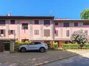 Ein Gebäude mit rosafarbenem Mauerwerk, ein geparktes Auto mit 'interhome'-Branding und eine gepflasterte Straße.
