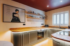 Eine moderne Küche mit eingebauten Geräten, Holz Arbeitsplatten und einem Weinkühlschrank.