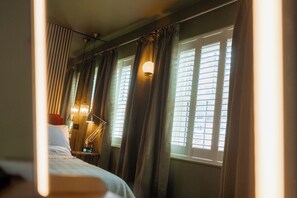 A hotel room with a bed, a nightstand with a lamp, and a window with blinds. - Stylish Townhouse in Shrewsbury Town Centre (Shrewsbury)