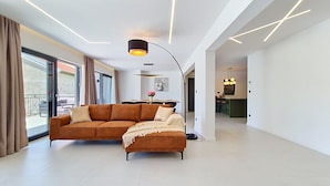 Una sala de estar moderna con un sofá seccional, un comedor y una cocina.