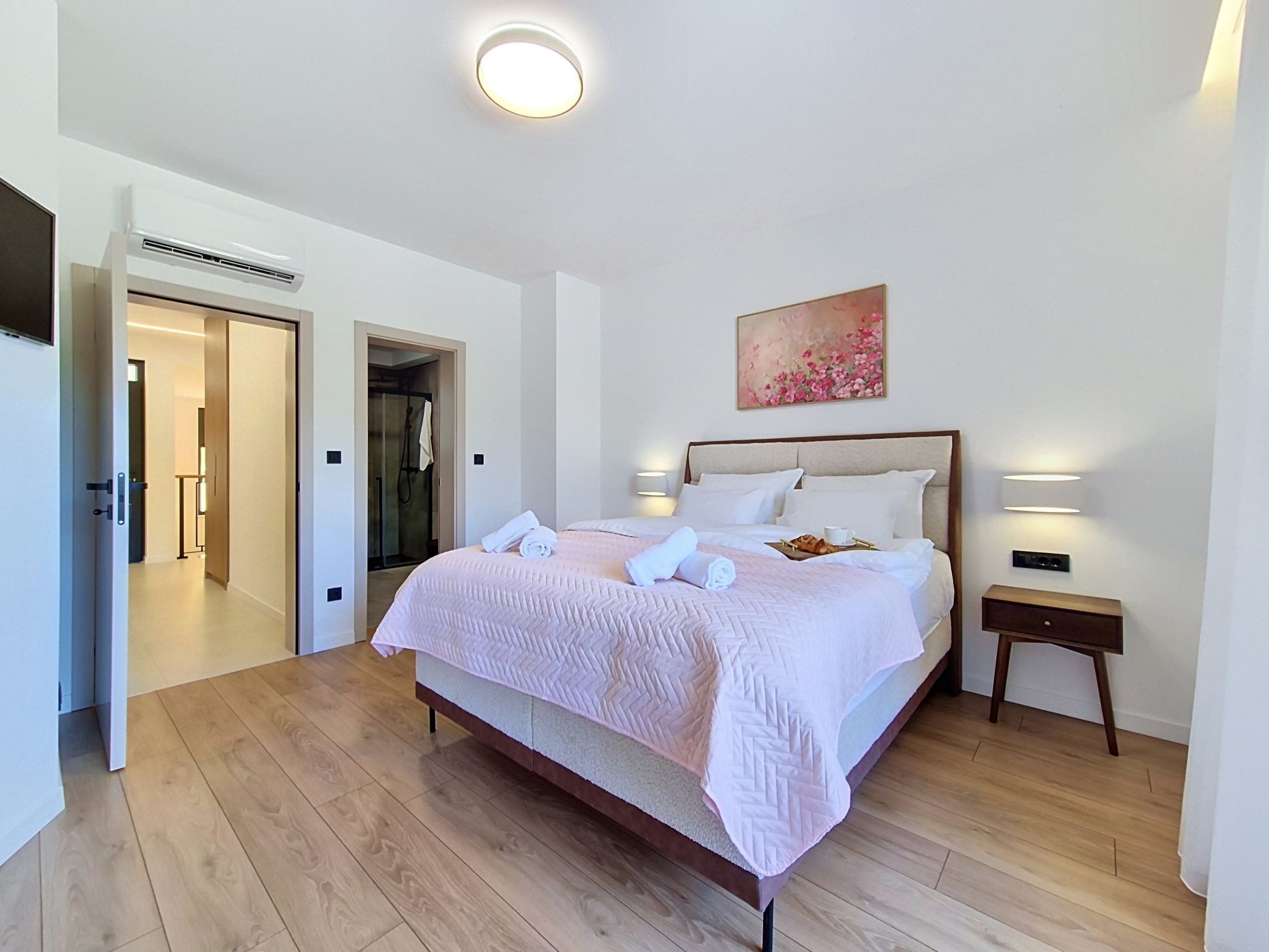 Une chambre d’hôtel avec un lit, une table de chevet, une lampe fixée au mur et un tableau.
